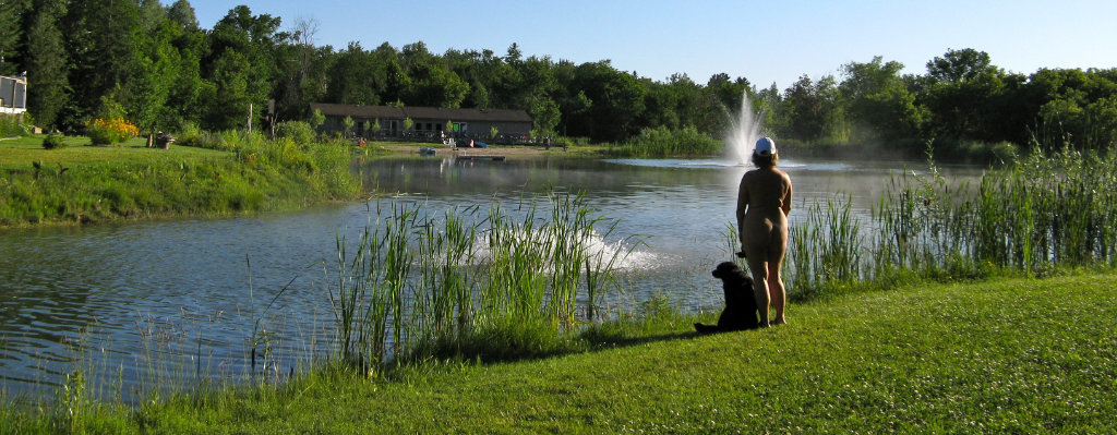 Woman and dog looking at the lake at Bare Oaks Family Naturist Park